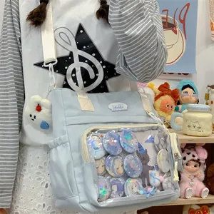 Detailed view of a light blue ita bag with a transparent window showing anime pins