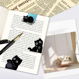 Close-up of three decorative cute black cat magnetic bookmarks on an open book page