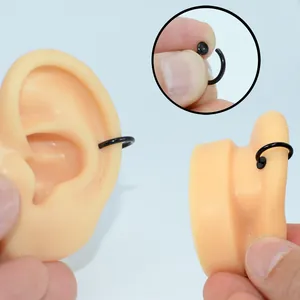 Vista detallada de pendiente de clip negro de 10mm en acero sobre modelo de oreja
