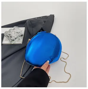 Primo piano di borsa da sera blu metallizzato con finitura a specchio e catena oro