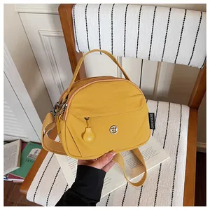 Bolso bandolera de nailon amarillo con asa superior y correa ajustable para diario.