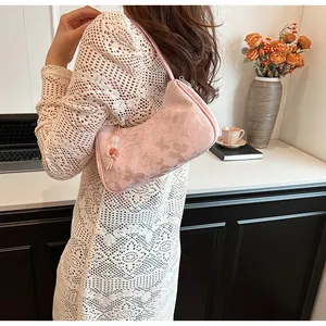 Elegant pink underarm bag with butterfly floral pattern shown on shoulder