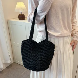 Close-up detail of a minimalist black hand-knitted crochet shoulder bag worn by a model