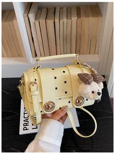 Close-up of retro cream yellow polka dot bag with cute teddy bear charm and gold locks.