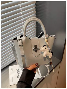 Gros plan d'un sac seau gris clair élégant avec un joli pendentif de cheval