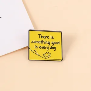 Detalle del pin de esmalte amarillo con forma de nota y cita inspiradora positiva