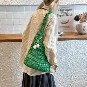 Modelo luciendo un bolso de hombro de ganchillo verde hecho a mano con diseño calado