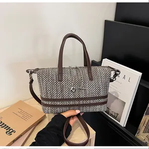 Detailed view of a retro woven bucket bag with chain charm and brown leather handles.