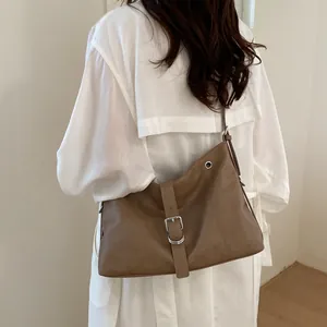 Detailed back view of a woman wearing a stylish brown hobo bag over a white outfit.