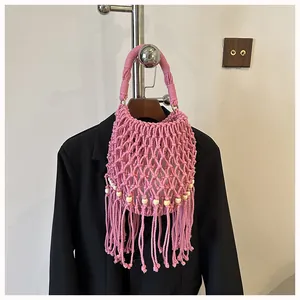 Detailed close-up view of a pink hand-woven macrame bucket bag featuring tassels and beads.