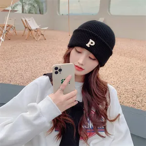 Fashionable black winter knit beanie featuring a white embroidered letter P on a model