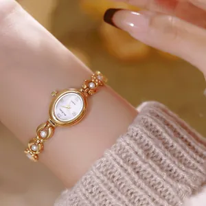 Elegante orologio ovale dorato con cinturino di perle indossato al polso