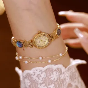 Detalle de elegante reloj de pulsera dorado con nácar de abulón y toques de perlas
