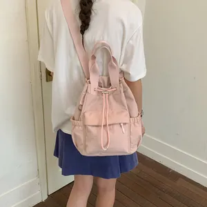 Vista trasera de una modelo con una mochila rosa con cordón y múltiples bolsillos