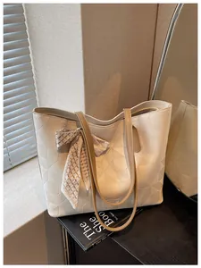 Close-up of a cream-colored large geometric textured tote bag with a patterned scarf detail