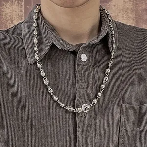 Detailed view of vintage silver-plated skull necklace on a male model's neck