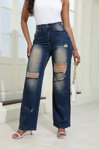 Full body view of high-waisted distressed blue denim jeans featuring large knee rips