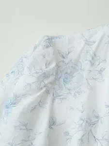 Dettaglio ravvicinato di tessuto bianco con elegante stampa floreale blu sulla manica