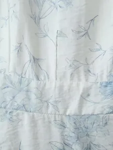 Dettaglio del tessuto bianco con stampa floreale azzurra su un abito sciancrato
