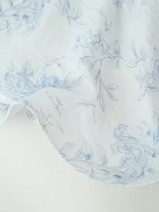 Primo piano dell'elegante motivo floreale blu sul leggero tessuto di un abito estivo