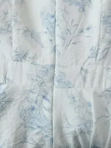 Dettaglio ravvicinato di stampa floreale blu su tessuto bianco con cerniera invisibile