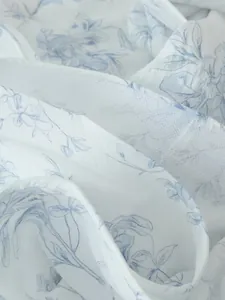 Vista dettagliata del tessuto bianco leggero con una delicata stampa floreale blu