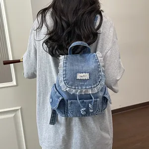Vista posteriore di uno zaino in denim blu con volant in pizzo bianco su una maglietta grigia.