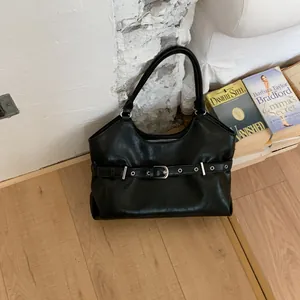 Chic black tote bag with buckle detail shown in a cozy indoor lifestyle setting