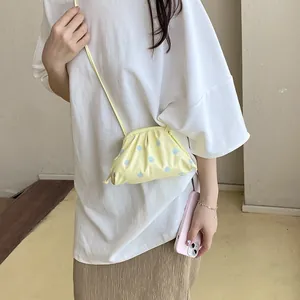 Close-up view of a stylish yellow polka dot dumpling crossbody bag worn by a model