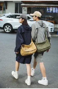 Asian models wearing yellow and olive green canvas messenger bags on a busy city street