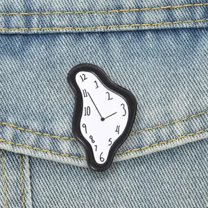 Detalle de un pin de esmalte con forma de reloj derretido inspirado en Salvador Dalí en denim