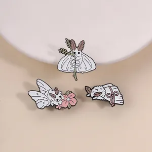 Vue macro de trois broches en émail de papillon-caniche blanc avec fleurs et rubans