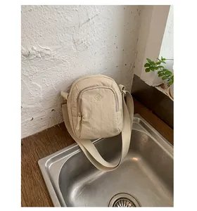 Detailansicht einer minimalistischen, cremefarbenen Mini-Umhängetasche aus Nylon für Handys