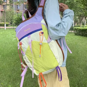 Close-up of a vibrant dopamine-colored outdoor hiking backpack worn by a model in a park.