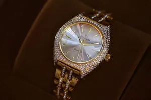 Primer plano de un reloj de lujo para mujer en tono dorado con bisel de cristales brillantes.