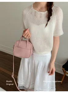Detaillierte Nahaufnahme der rosa Handtasche mit Lychee-Struktur von einem Modell.
