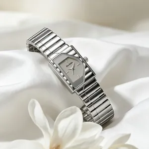 Reloj vintage de acero plateado con esfera geométrica gris sobre fondo de seda blanca pura