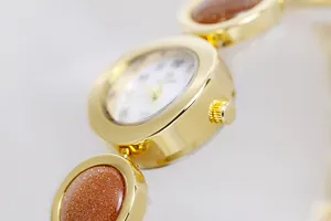 Primer plano de un elegante reloj de cadena dorado con incrustaciones de piedra estelar.
