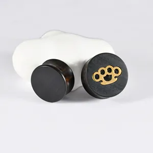 Detailed view of ebony wood ear plugs featuring a gold brass knuckle pattern metal inlay
