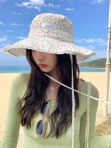 Stylish woman wearing a floral lace bucket hat with a wide brim on a sunny beach day.