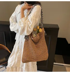 Détail du grand sac cabas en paille tressée avec une bandoulière élégante à rayures
