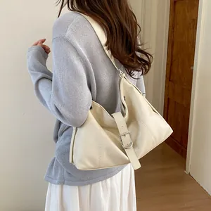 Stylish cream white hobo shoulder bag worn by model in casual indoor setting.