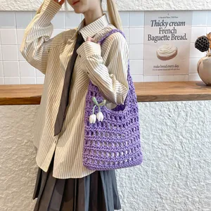 Vista detallada de un bolso de hombro de punto morado con un dije de tulipán.