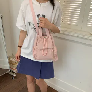 Modelo con una mochila de nailon rosa con cordón en un entorno interior mínimo