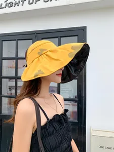 Detailed side view of a yellow sun hat with butterfly pattern and black vinyl lining
