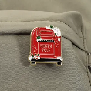 Detailansicht einer festlichen roten Weihnachts-Briefkasten-Emaille-Pin auf grünem Stoff.