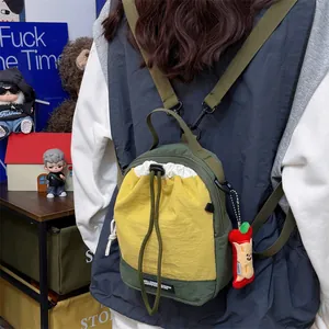 Detailansicht einer kleinen gelb-grünen Umhängetasche aus Nylon, die über einer Weste getragen wird.