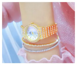 Primer plano de un reloj de pulsera dorado con pedrería completa y pulseras a juego