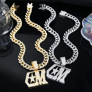 Detailweergave van de vergulde CM-letter hanger met een stoere schakelketting