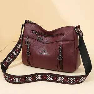 Large burgundy crossbody handbag with multiple pockets and patterned jacquard strap